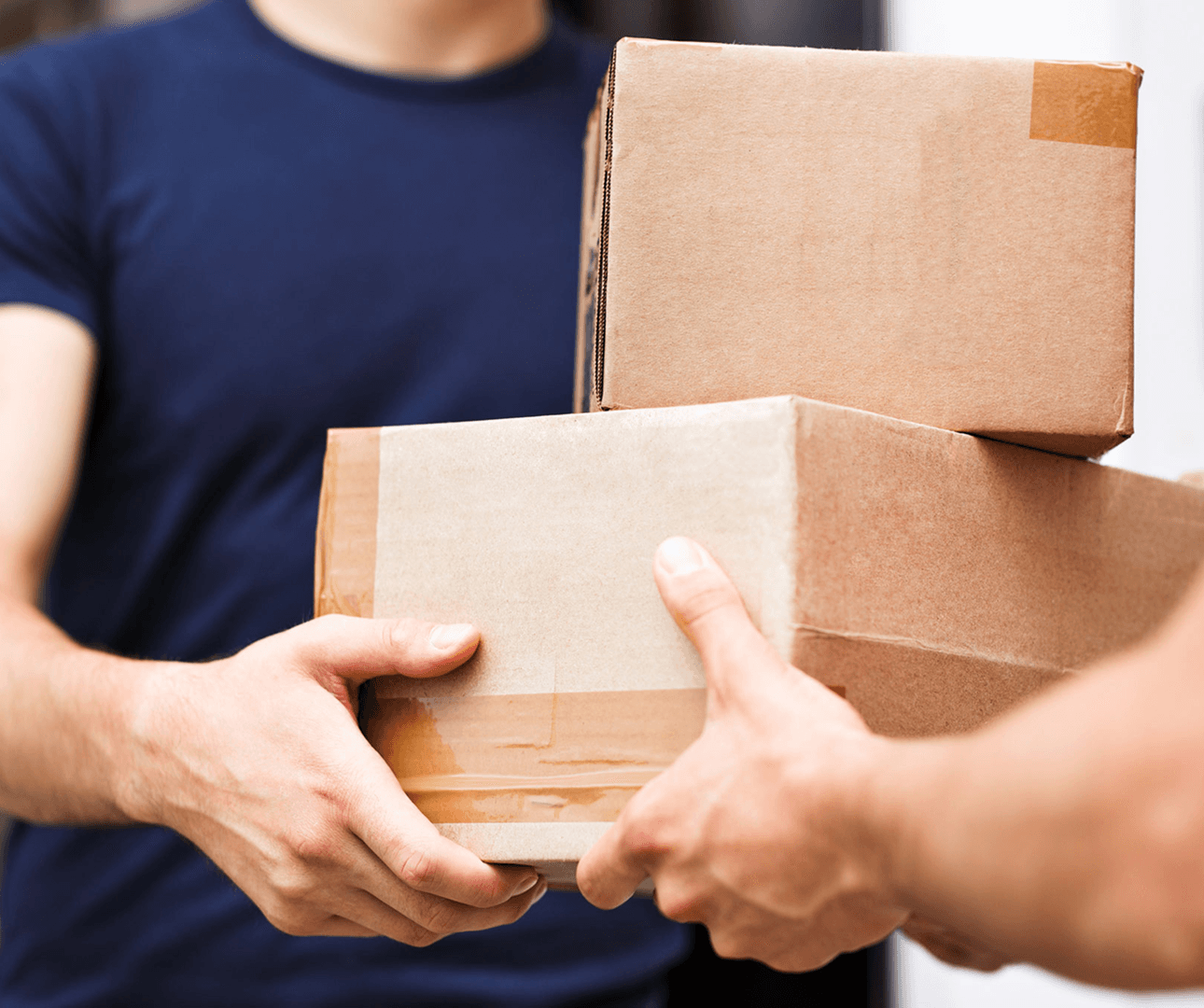 Hands exchanging stacked delivery boxes.